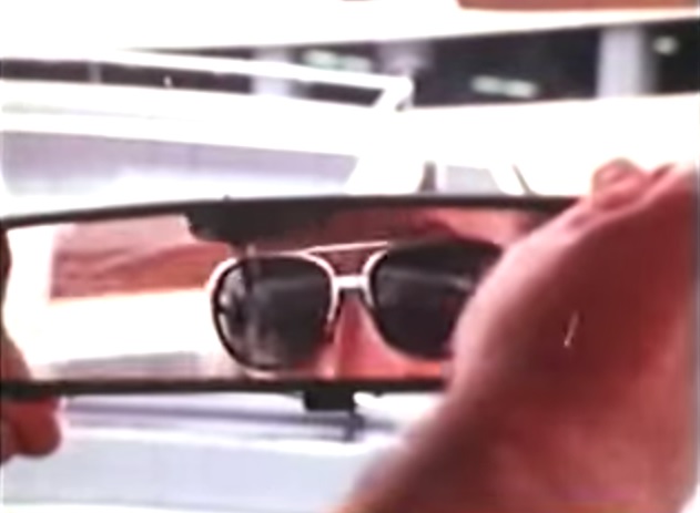 Reyner Banham adjusting his rear-view mirror.